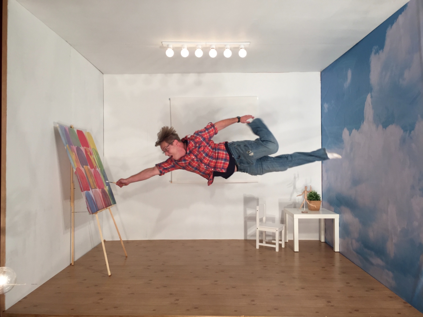 Chad Church floating next to a painting on an easel in his studio